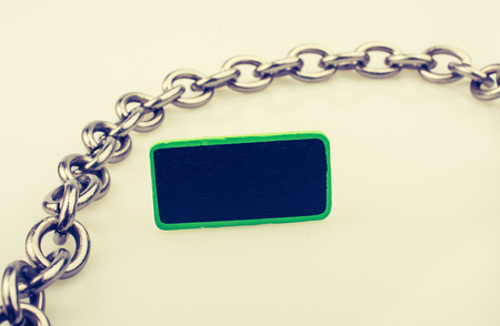 Small green sided black noticeboard surrounded by chain on a white backgroundの写真素材