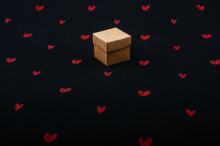 Brown cardboard box on black background with red heartsの写真素材