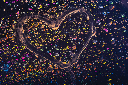 Heart on a glass with paint splash effect on it on a black backgroundの写真素材