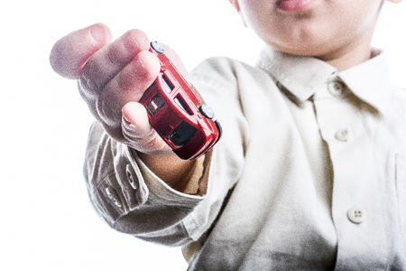 baby hand holding a red car on a white backgroundの写真素材