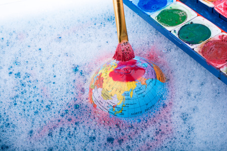 Paint dissolving through painting brush on the top of globeの写真素材