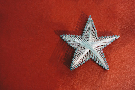 A star made from steel nails and string on a red background