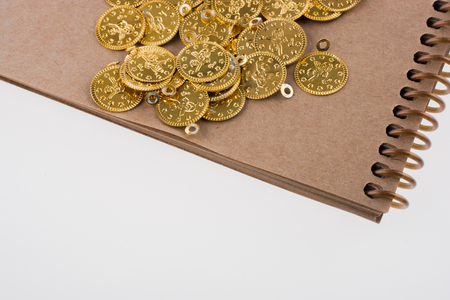 Spiral notebook and the gold coins on white backgroundの写真素材