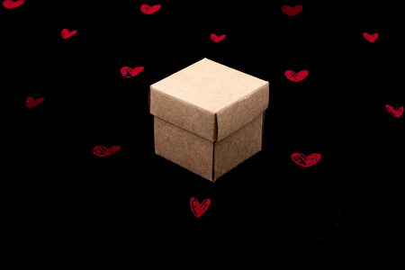 Brown cardboard box on black background with red heartsの写真素材