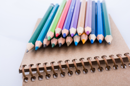 Color pencils  placed on a spiral brown notebookの写真素材