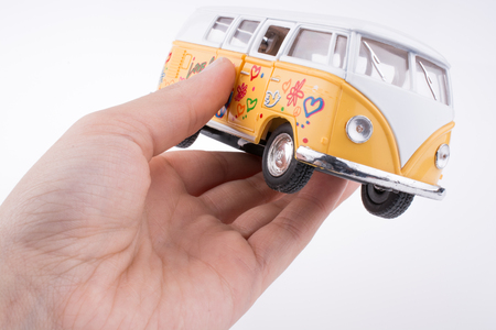 Hand holding a yellow Peace Van on a white backgroundの写真素材