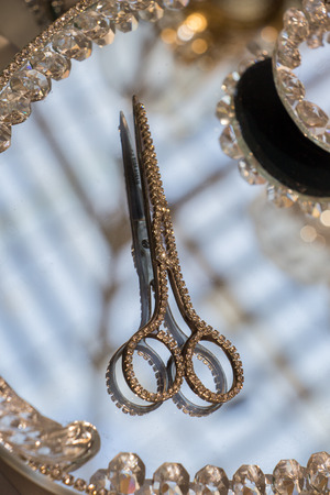 Metal scissors with diamonds on it on a mirrorの写真素材