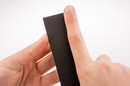 Hand holding a piece of black paper on a whiteの写真素材