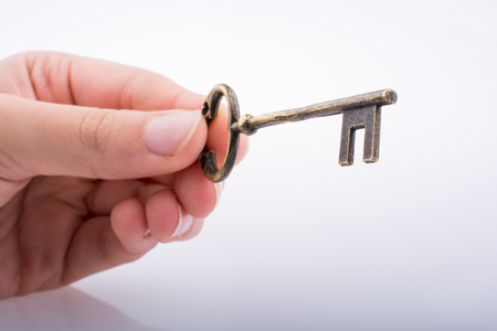 Hand holding a key on a white backgroundの写真素材