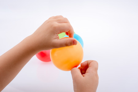 Hand holding a Colorful small balloon with colorful balloons on the  white backgroundの写真素材