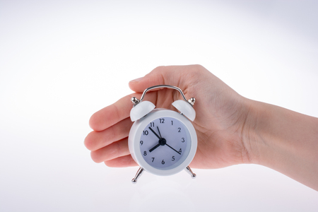 Alarm clock in hand on a white backgroundの写真素材