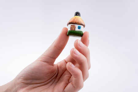 Hand holding a small traditional hut on a white backgroundの写真素材