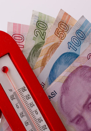 Turkish Lira banknotes by the side of a red color temperature on white backgroundの写真素材