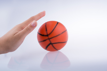 Hand holding an orange basketball model on a white backgroundの写真素材