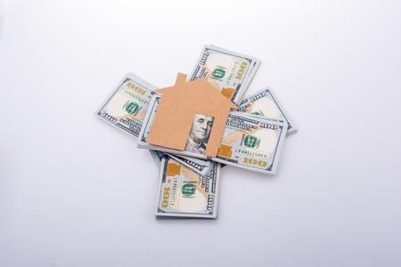 Paper house placed beside a bundle of US dollar banknoteの写真素材
