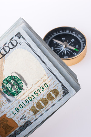 American dollar banknotes by the side of a compass on white backgroundの写真素材