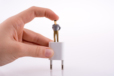 Hand holding a human figure on a white adapterの写真素材