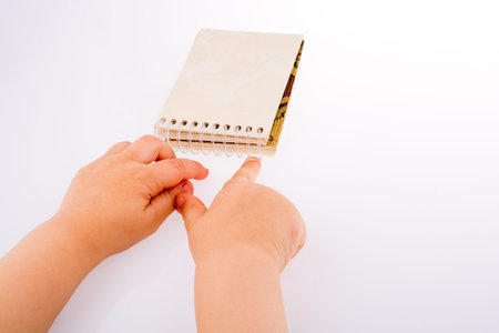 Baby holding a Spiral blank notebook on a white background