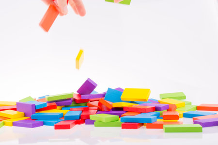 Hand playing with colored domino on white background