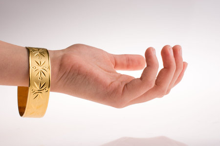 Hand with a golden bracelet on a white background