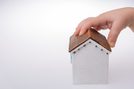 Little model house and  a hand  on a light white color backgroundの写真素材