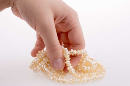 Hand holding pearl necklace on white backgroundの写真素材