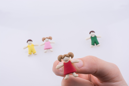 Hand holding colorful dressed children figure on a white backgroundの写真素材
