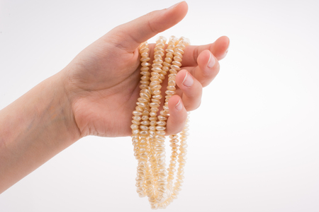 Hand holding pearl necklace on white backgroundの写真素材