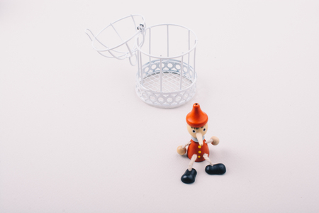 Metal cage and Little puppet pinocchio made of woodの写真素材