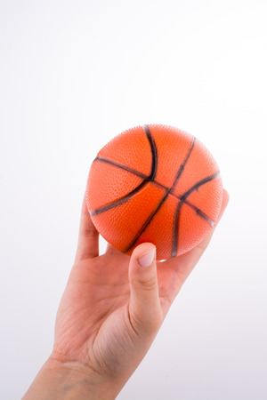 Hand holding an orange basketball model on a white backgroundの写真素材
