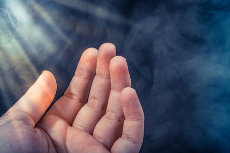 Hand making a gesture on a black smoky backgroundの写真素材