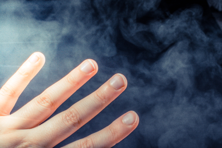 Hand making a gesture on a black smoky backgroundの写真素材