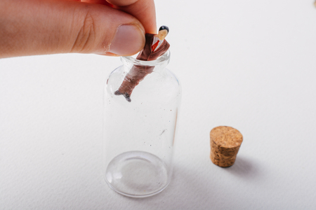Hand putting  figurine of  model in bottleの写真素材