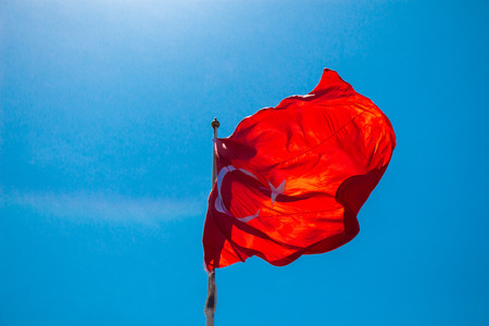 Turkish national flag with white star and moon in skyの写真素材