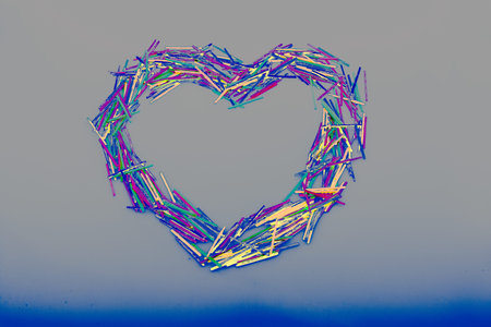 Coloured wooden  sticks form heart shape on white