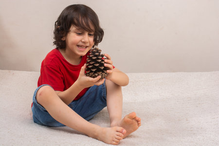 Little boy is holding pine cone in hand on white backgroundの写真素材