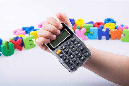 Little calculator in hand with colorful letters behind on whiteの写真素材