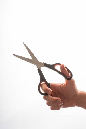 Hand holding steel scissors on a white backgruondの写真素材