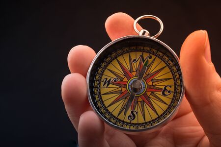 Hand is holding a magnetic compass on black backgroundの写真素材