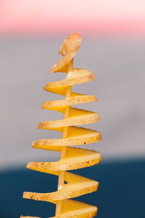 Peeled spiral potatoes for frying on wooden sticksの写真素材