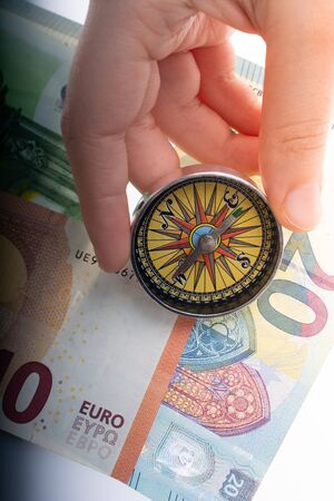 Compass in hand on Euro banknotes with Euro currency finance directionの写真素材