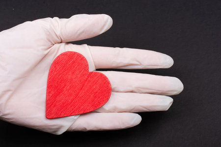 Hand in sterile glove hold a heart. Concept of health care