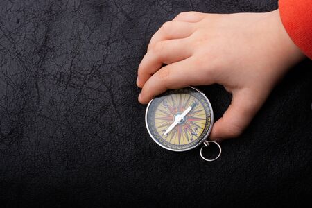 Hand is holding a magnetic compass on black backgroundの写真素材