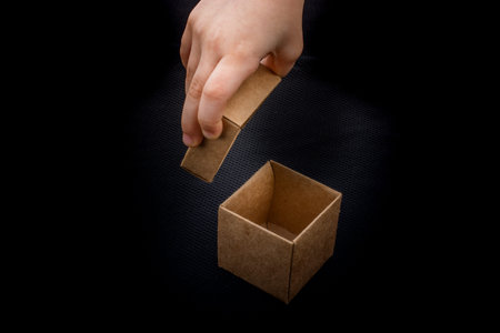 Hand opening a brown cardboard box on black backgrounds