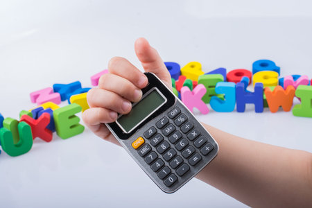 Little calculator in hand with colorful letters behind on white