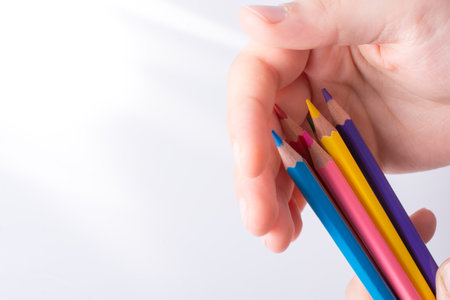 Hand holding color Pencils placed on a white backgroundの写真素材