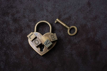 Love shaped padlock, key and love wording on black backgroundの写真素材