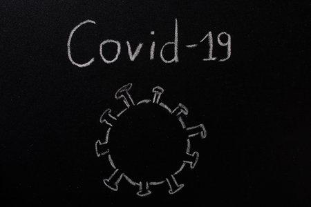COVID-19 Words on a Black Chalk Board.