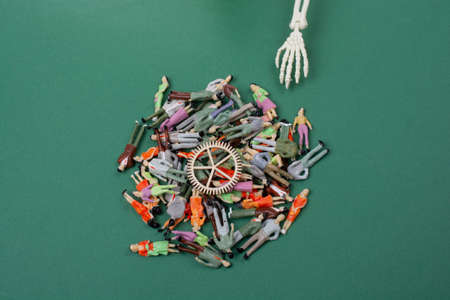 Skeleton hand pressing on man figurine on red .  Death conceptの写真素材