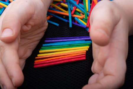 Kid playing with coloured wooden  sticks for creativity on white backgroundの写真素材